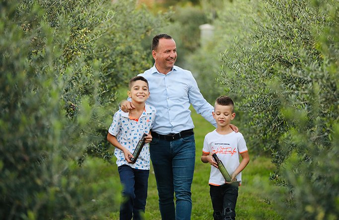 Porodica Lučka Olive u maslinjaku sa bocama ekstra djevičanskog maslinovog ulja